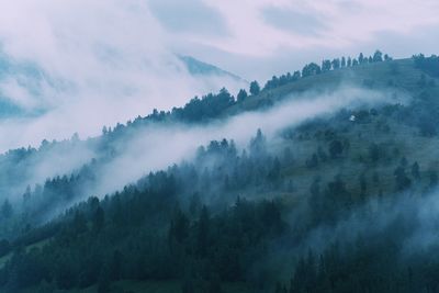Scenic view of misty mountains against cloudy sky