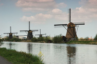 Traditional windmill by river against sky