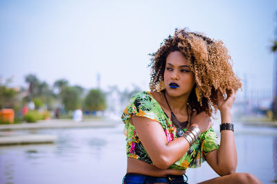 Close-up of confident woman at lake against sky