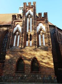 Low angle view of cross on building against sky