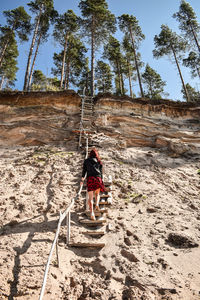 Rear view of woman moving up on steps at beach