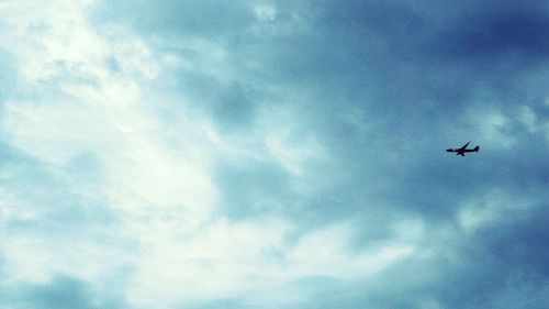 Low angle view of silhouette airplane against sky