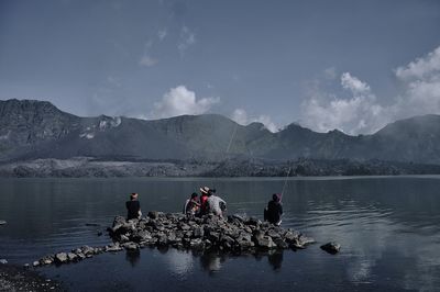 People on lake against mountain range