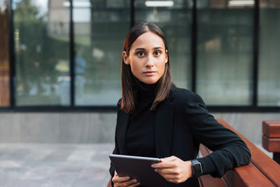 Portrait of young woman using digital tablet while sitting at office