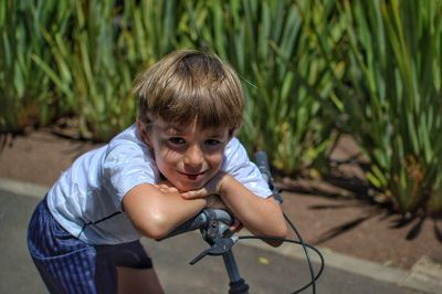 Portrait of boy sitting on bicycle in city