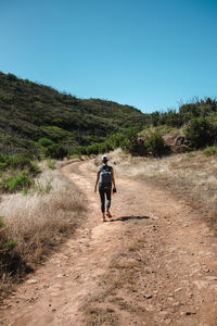 Rear view of man walking on dirt road