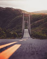 Empty road by mountain against sky