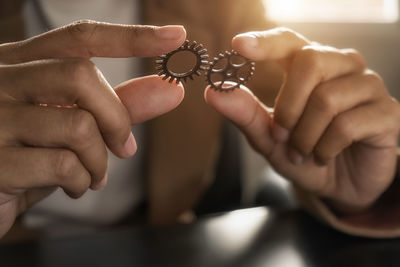 Midsection of person holding gears on table