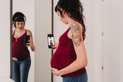 Pregnant woman photographing in front of mirror