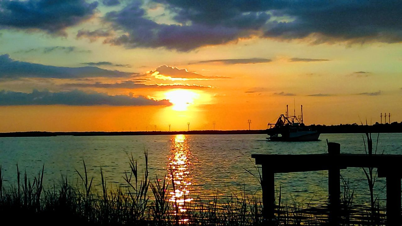 SILHOUETTE OF BOATS IN SEA DURING SUNSET