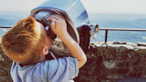 Close-up of boy looking through coin operated binoculars