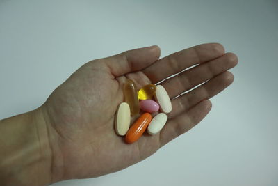 Close-up of hand holding leaf over white background