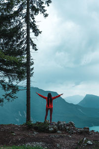 Rear view of woman with arms outstretched standing on snow covered mountains