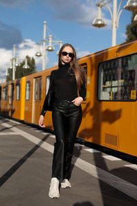 Portrait of young woman standing against train