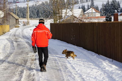 Rear view of woman with dog on snow