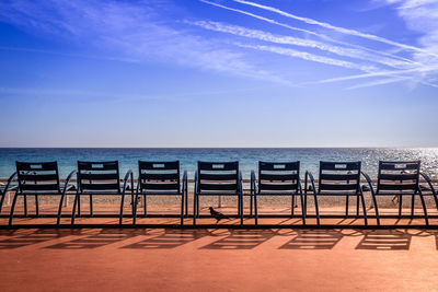 Chairs arranged against sea at beach