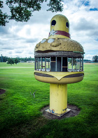 Trees on grassy field against cloudy sky