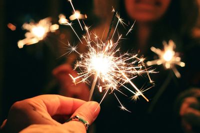 Close-up of hand holding sparkler at night