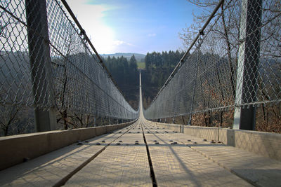 Footpath amidst fence against sky, hanging rorope bridge