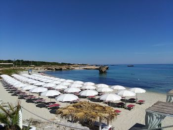 Parasols at beach against blue sky