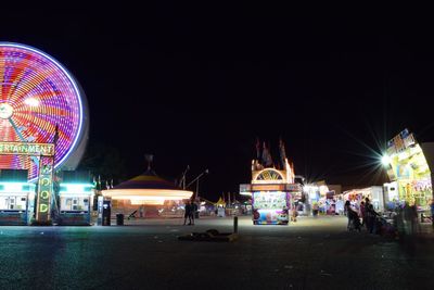 Illuminated ferris wheel in front of amusement park