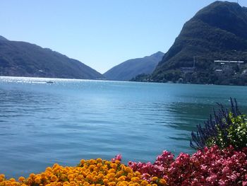 Scenic view of lake by mountains against clear blue sky