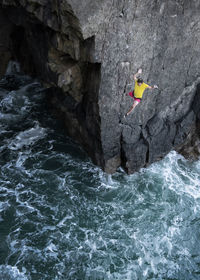 Male rock climber jumping in sea from cliff