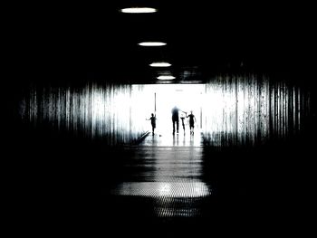 Silhouette of man walking with kids in passage