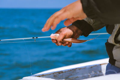 Close-up of hand holding sea against sky