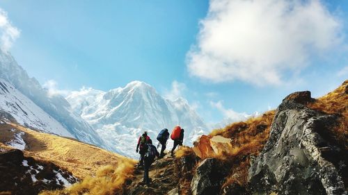 Hikers climbing on mountain against sky