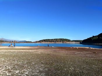 Scenic view of beach against clear blue sky