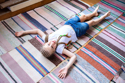 A beautiful cheerful girl with pigtails lies on the floor, on woven rugs. rest after exercise. 