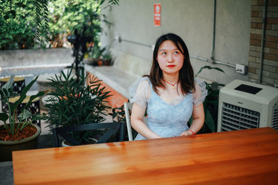 Portrait of young woman sitting on table