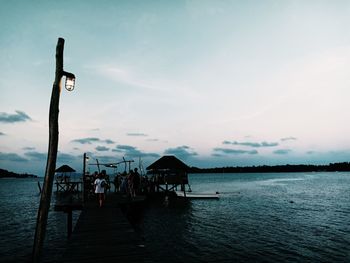 People on pier over sea against sky