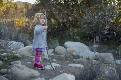 Girl holding stick while standing on field