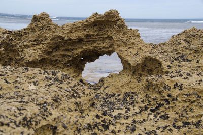 Rock formation on beach against sky