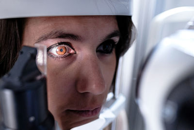 Closeup female patient with eye illuminated with light waiting for tonometer to finish measure intraocular pressure during eye examination in clinic