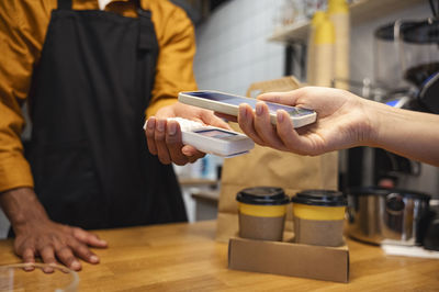 Customer paying for coffee using smart phone at cafe