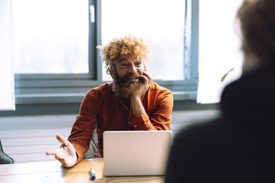 Smiling businessman discussing with colleague in office