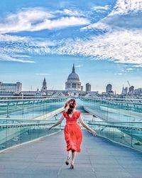 Woman with umbrella against sky in city