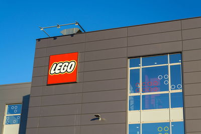 Low angle view of sign on building against clear blue sky
