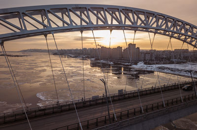 Bridge over river in city during sunset