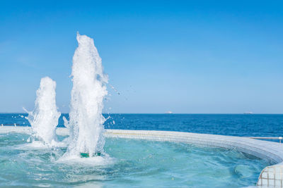 Water splashing in swimming pool against clear blue sky