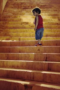 Full length of boy standing on staircase against brick wall