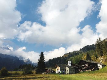 Houses and trees on field against sky