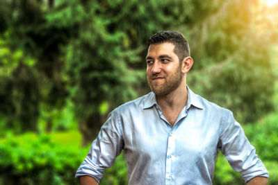 Thoughtful man standing against trees