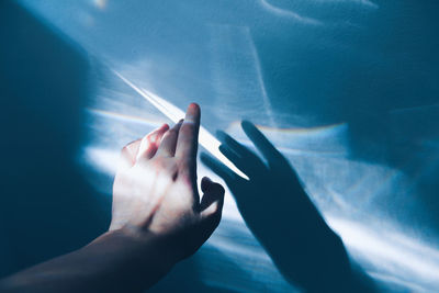 Cropped hand of woman touching rainbow on wall