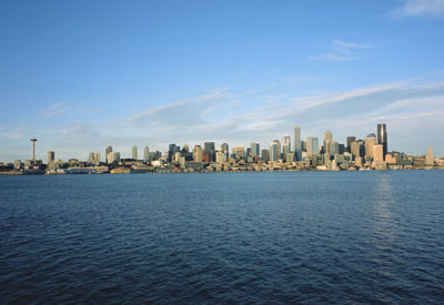 Sea and buildings in city against sky