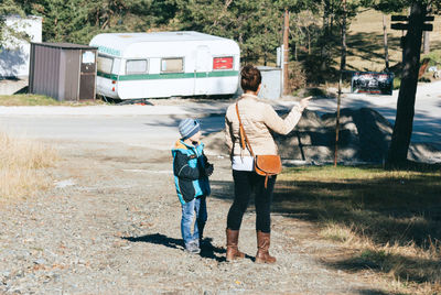 Rear view of woman with son standing on road