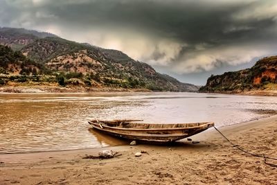 Boat moored on beach against sky